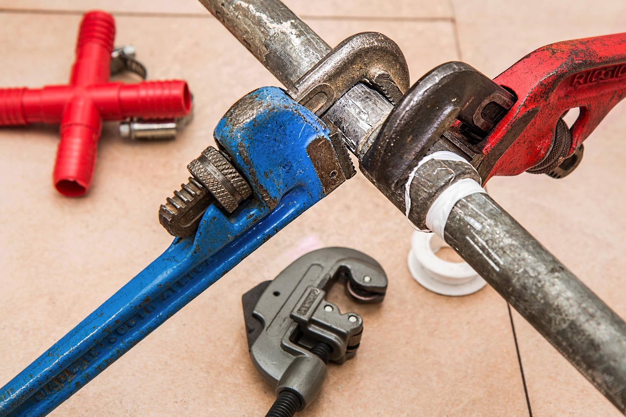 Pipe wrenches and plumbing tools laid out on a workbench
